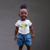 Child wearing a white t-shirt with text and blue shorts on a dark background
