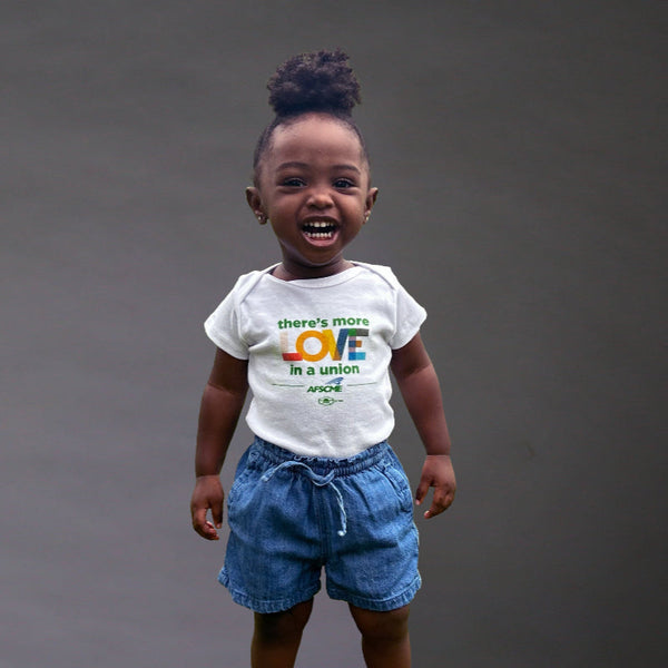 Child wearing a white t-shirt with text and blue shorts on a dark background