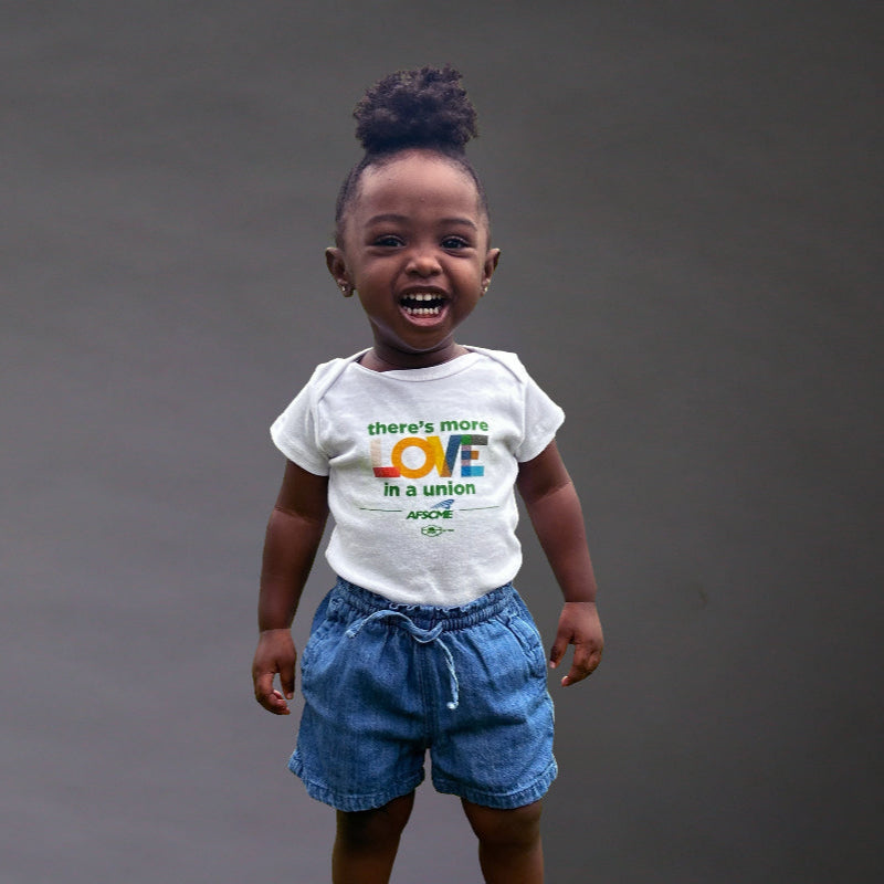 Child wearing a white t-shirt with text and blue shorts on a dark background