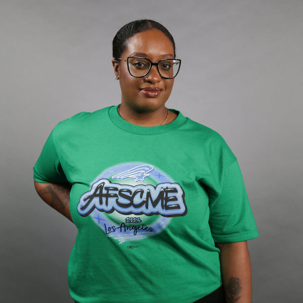 Person wearing a green t-shirt with a logo and text on a gray background